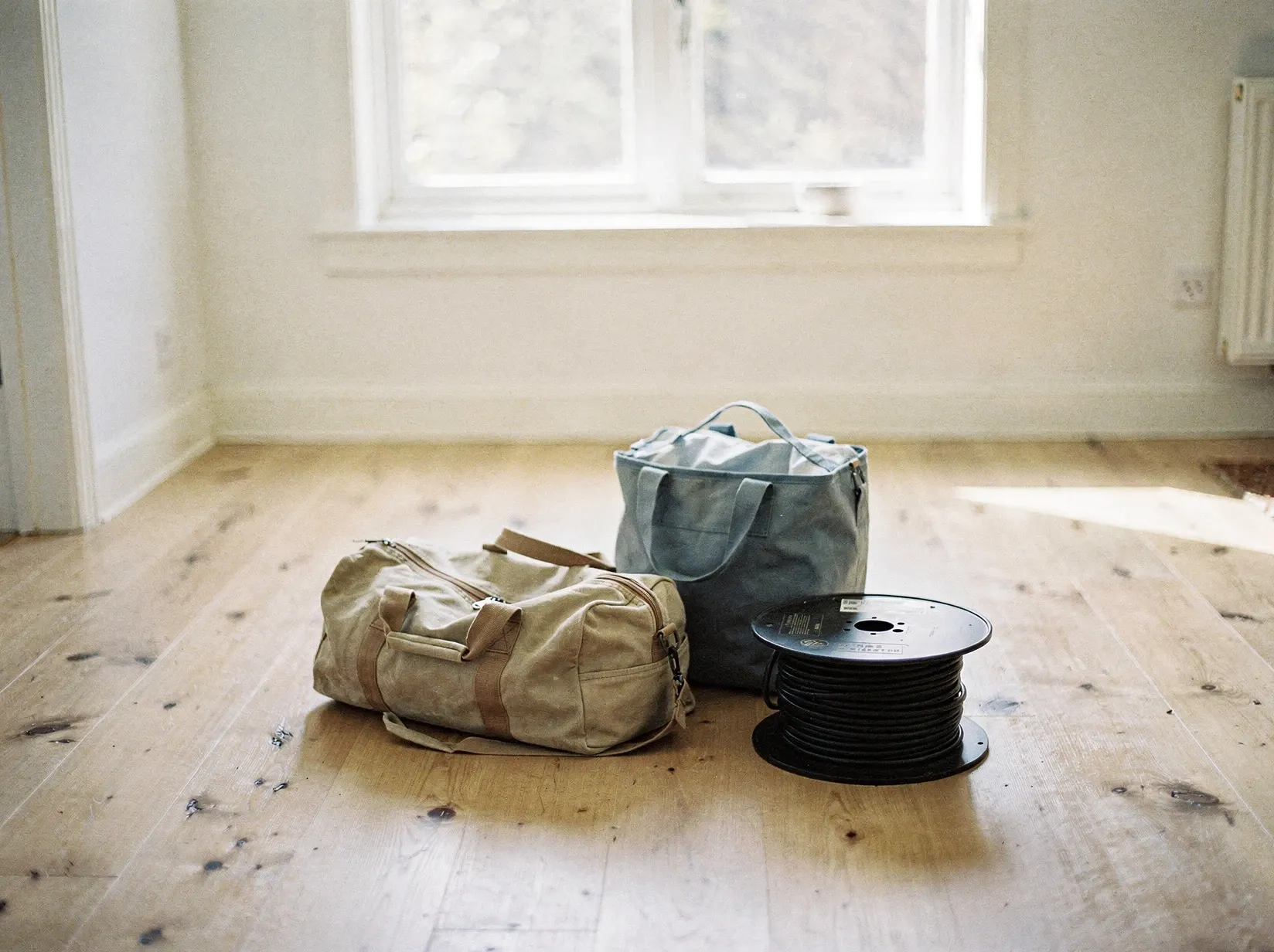 Wohnungsflur vor der Abfahrt mit gepackter Reisetasche, Kühltasche und einer Kabeltrommel neben der Wohnungstür